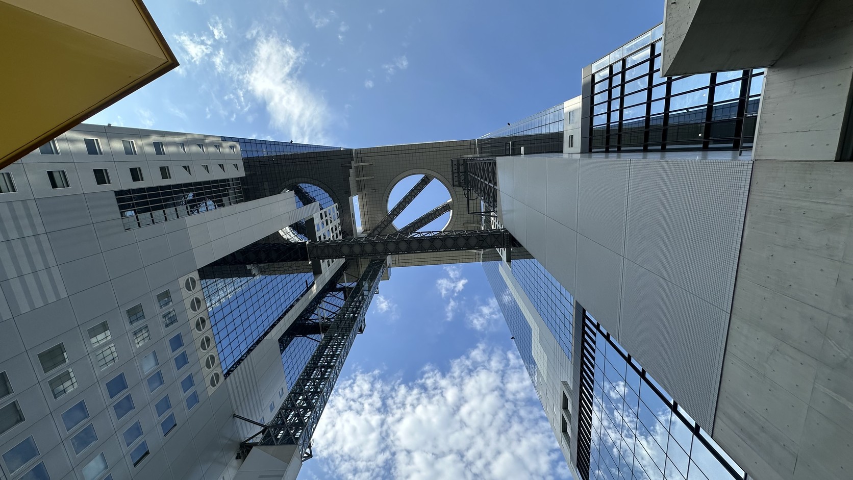 站在大廈下方仰望，兩棟大樓之間的空中庭園與連結的鋼骨結構