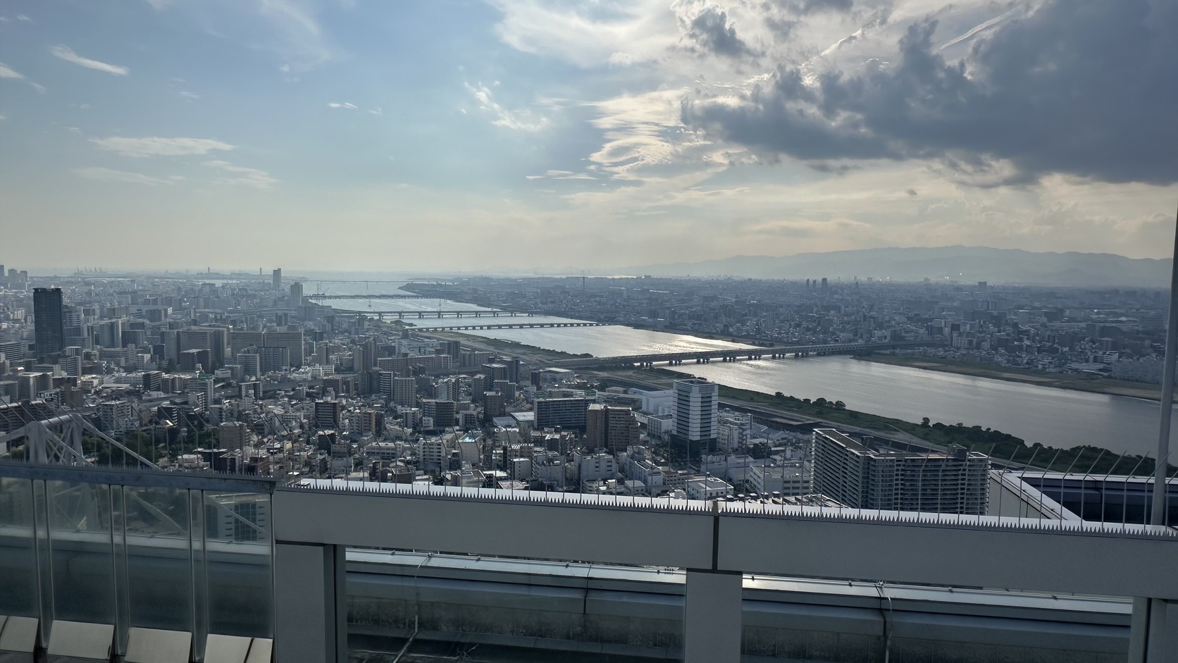 從屋頂眺望淀川與橫跨河面的橋梁，遠方有山