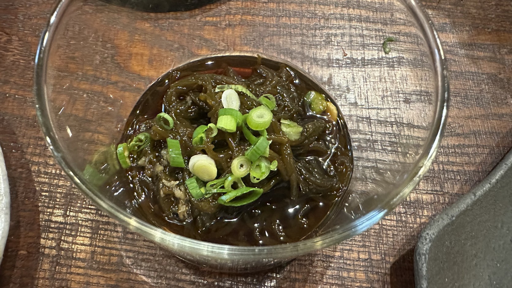 玻璃小碗裡的深褐色細絲狀海藻小菜，撒著蔥花