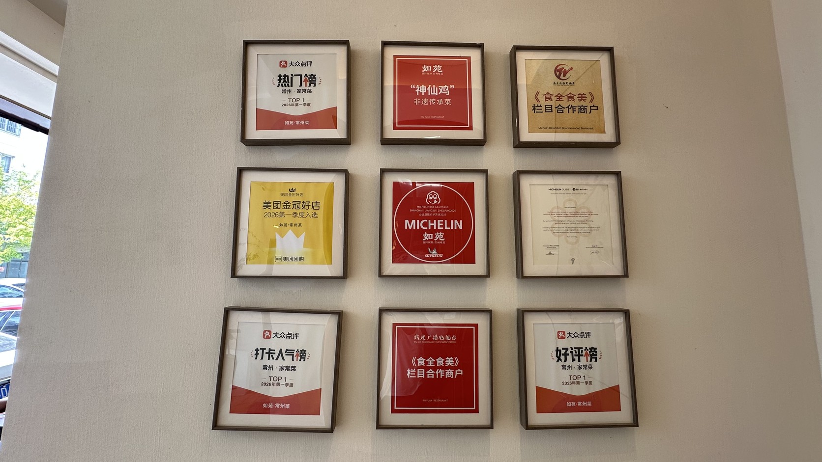 店內牆面上的九面獎牌，包括大眾點評榜單、美團金冠好店、米其林標誌，以及寫著「神仙雞」「非遺傳承菜」的牌子
