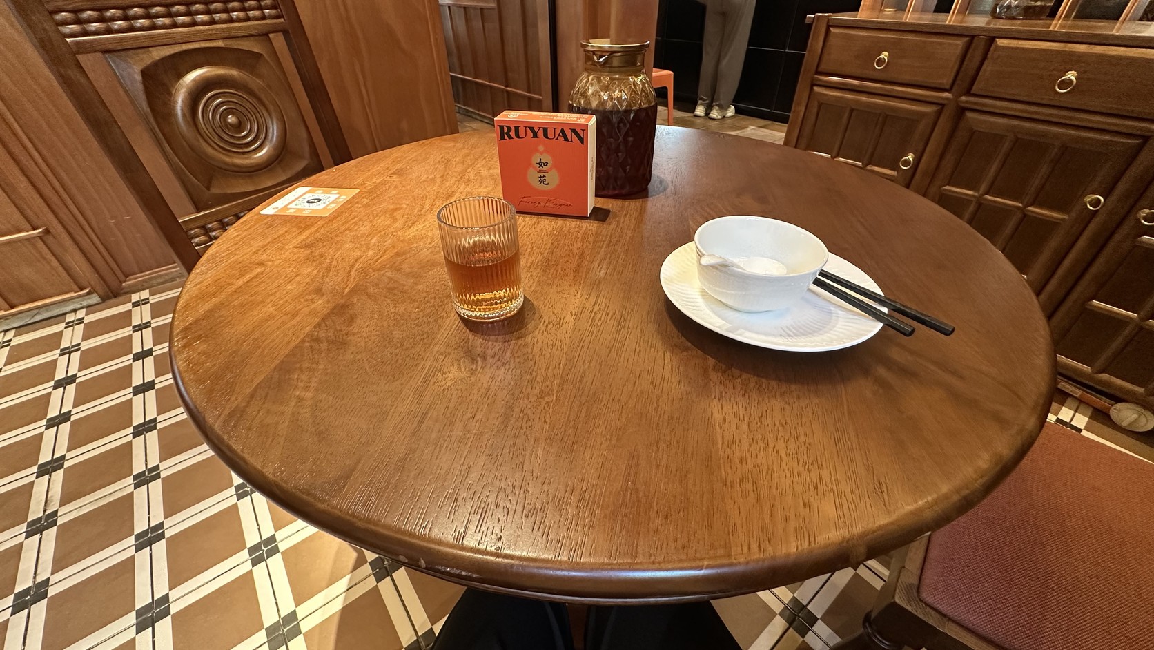 一個人使用的圓形木質四人桌，桌上放著茶杯、紙巾盒與餐具