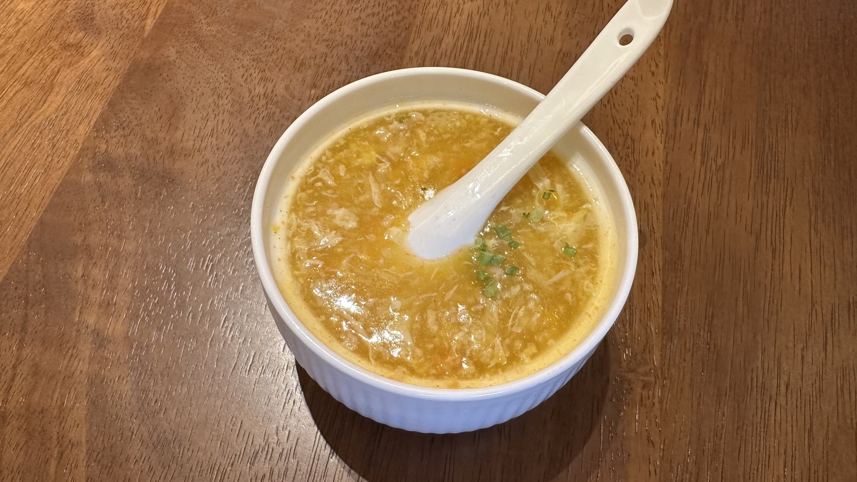 一碗黃褐色濃稠的老常州膩蟹糊，撒著蔥花，白色瓷匙放在碗中