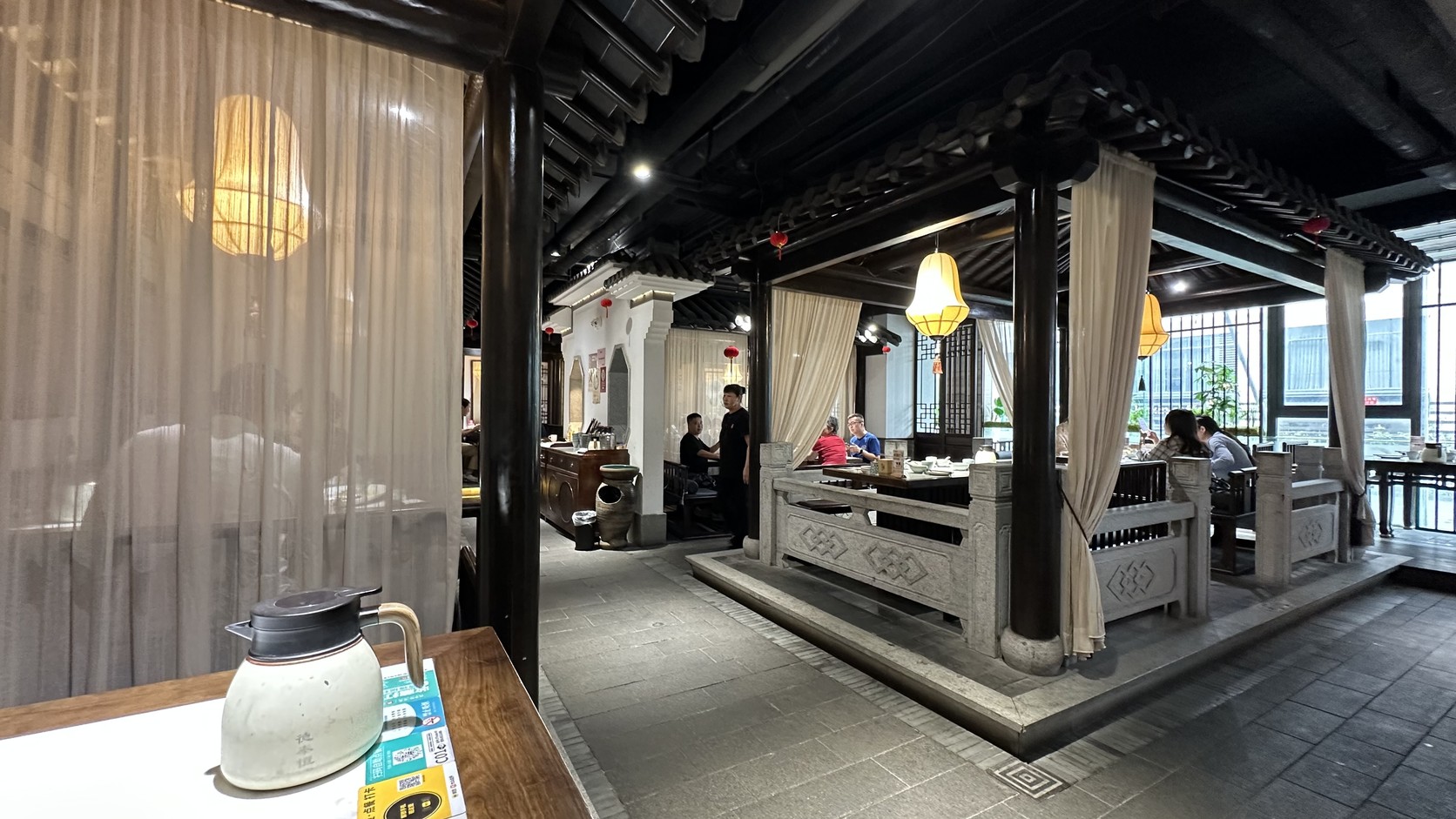 二樓用餐區，黑色木柱、灰瓦、石欄與米色簾幕圍出半獨立的院落式空間