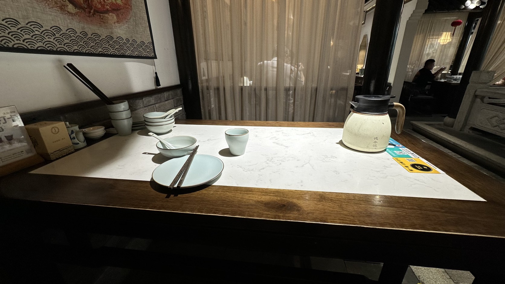 二樓用餐區的餐桌，桌上擺著碗、筷子與茶具，旁邊垂著米色簾幕