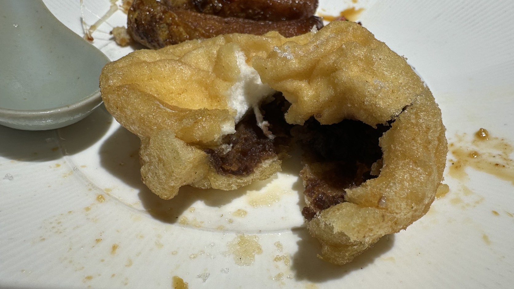 咬開的孝子網油卷，可見蓬鬆的蛋泡外皮與深色的紅豆沙內餡