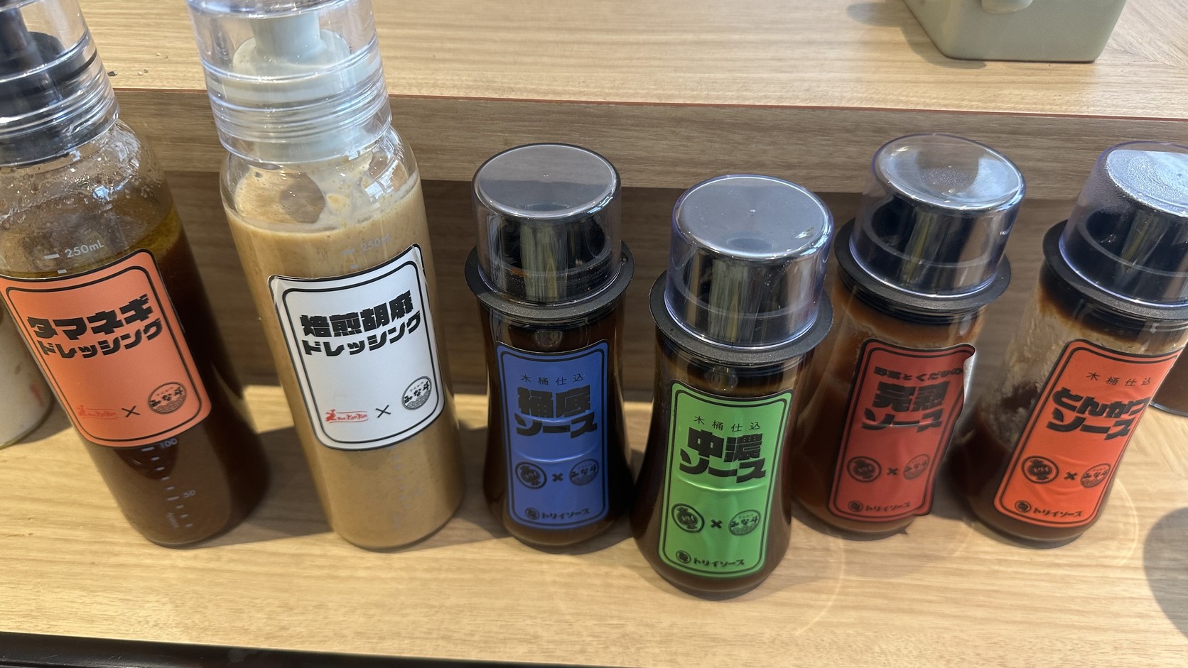 桌上的醬汁瓶：左邊是玉ねぎ與焙煎胡麻兩種沙拉醬，右邊是桶底、中濃、完熟與とんかつ四種醬汁