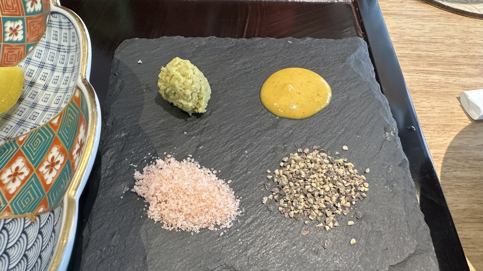 黑色石板上的四種調味：山葵、黃芥末、粉紅色的鹽與黑胡椒