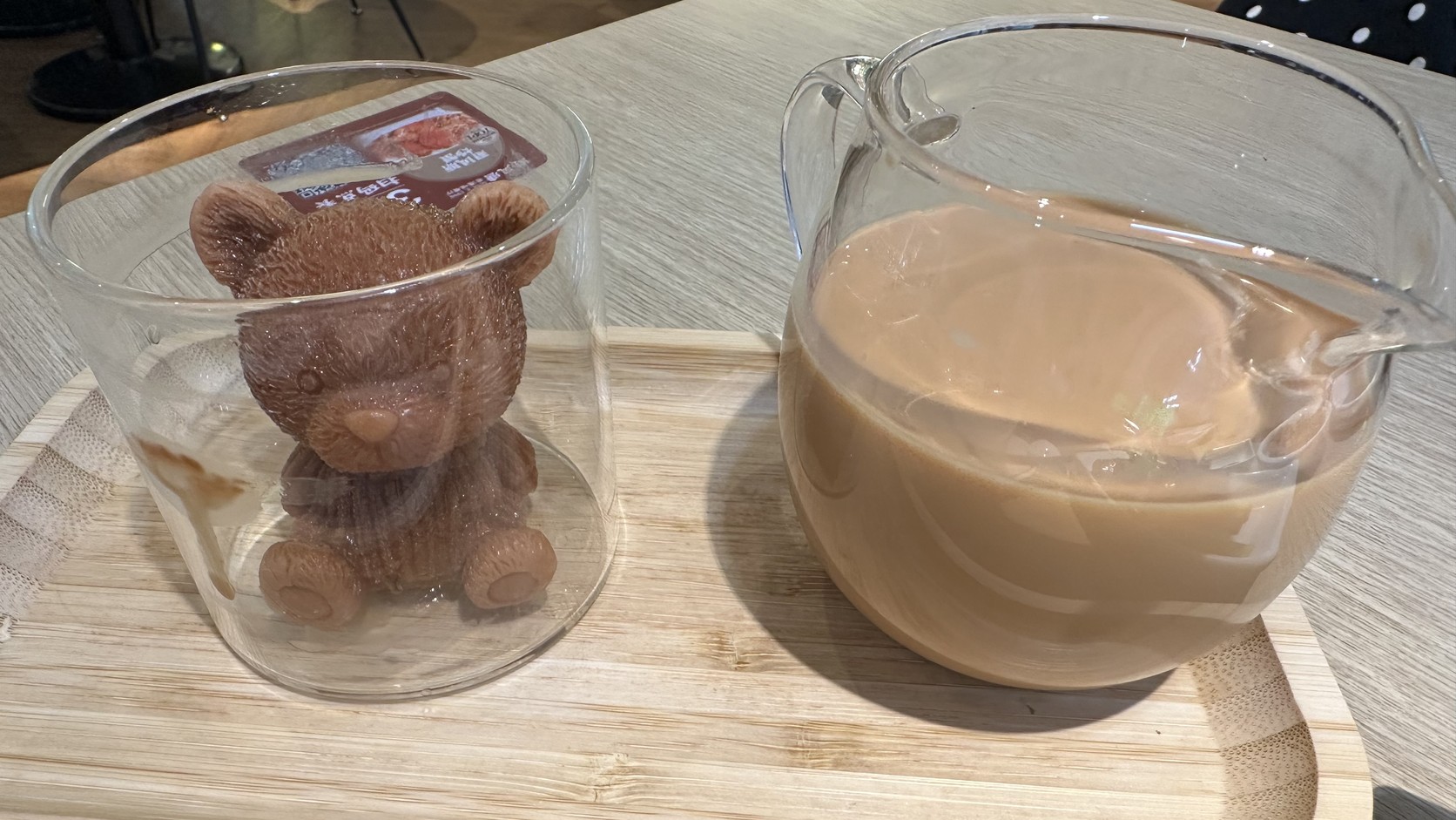 小熊冰塊與奶茶壺實拍，透明玻璃杯裡坐著一隻茶褐色的小熊造型冰塊，旁邊是裝著港式奶茶的玻璃壺