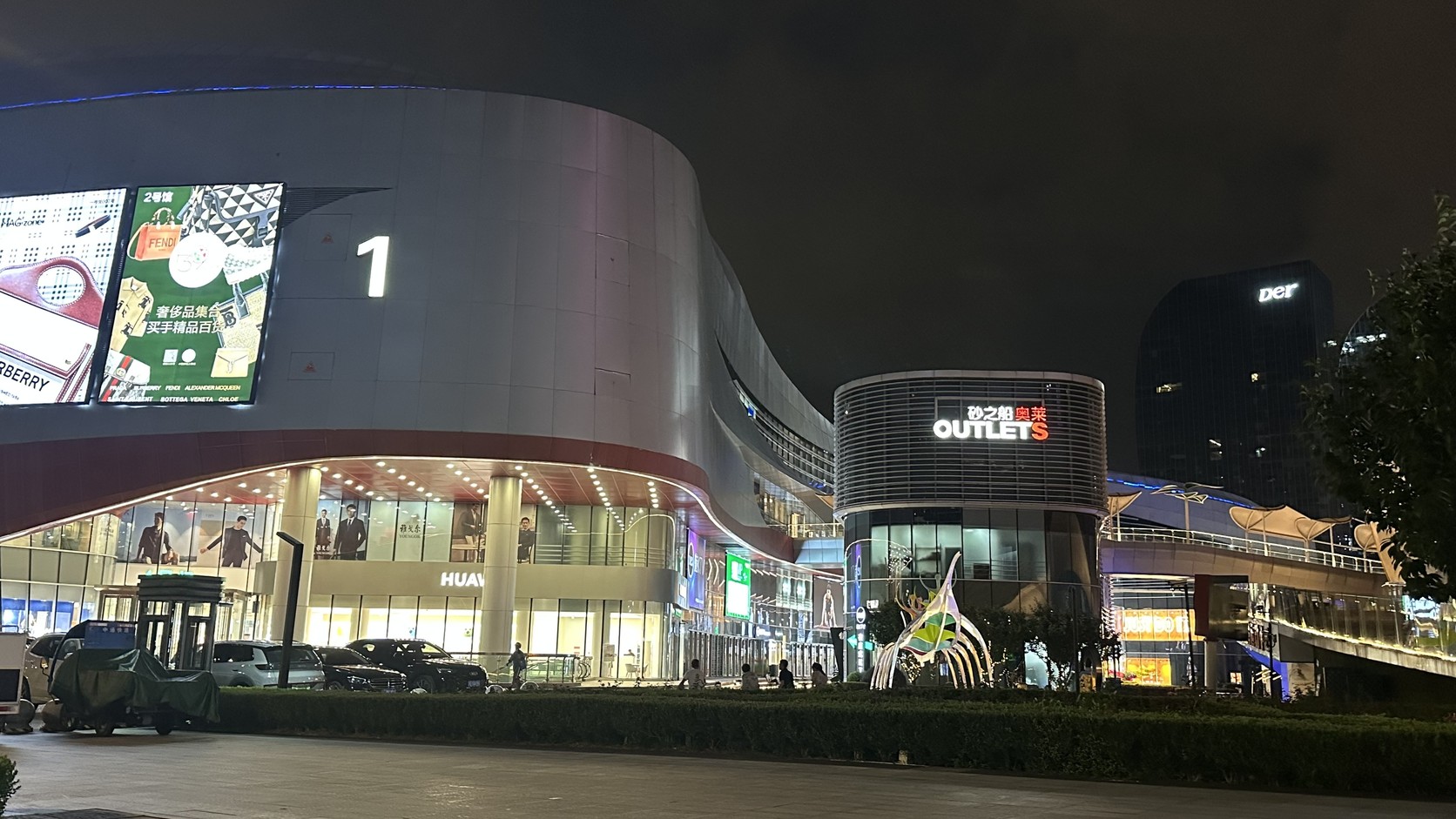 砂之船奧萊商場的夜間外觀實拍，外牆有「砂之船 OUTLETS」字樣