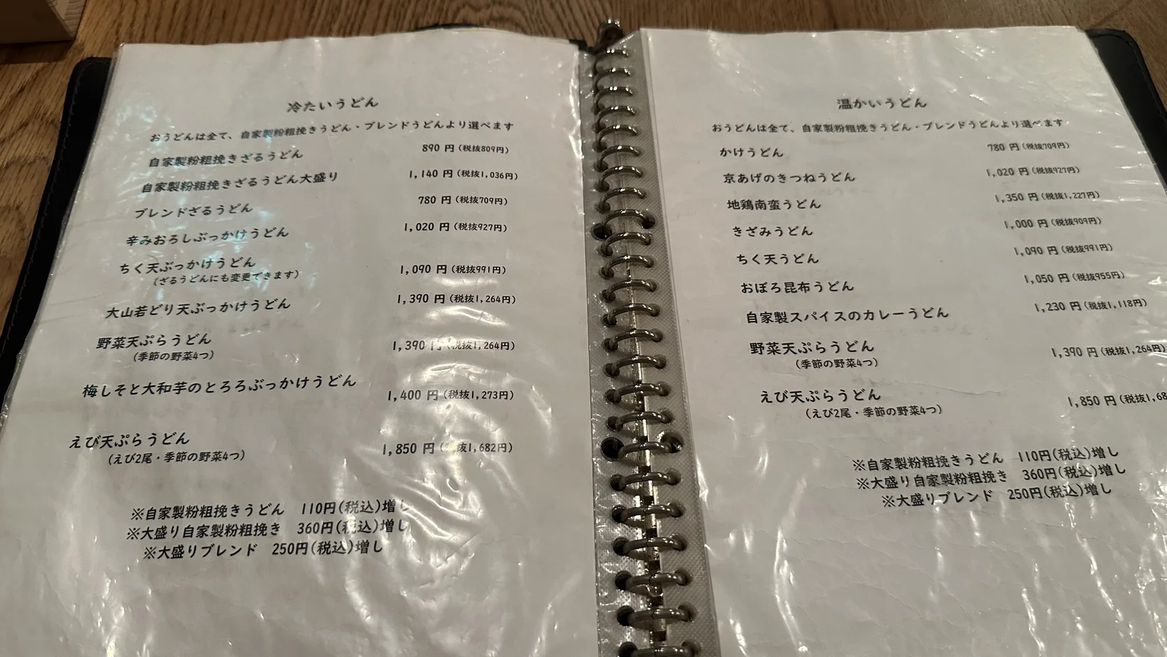青空blue店內菜單本：左頁為冷たいうどん，右頁為温かいうどん，註明所有烏龍麵都可選自家製粉粗挽きうどん或ブレンドうどん