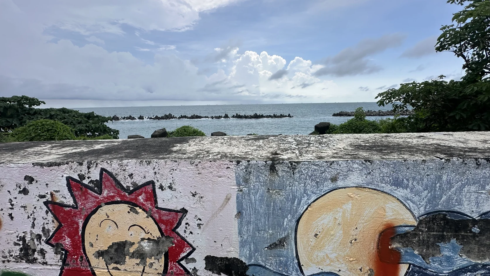 斑駁的海濱彩繪牆，後方是一望無際的海面