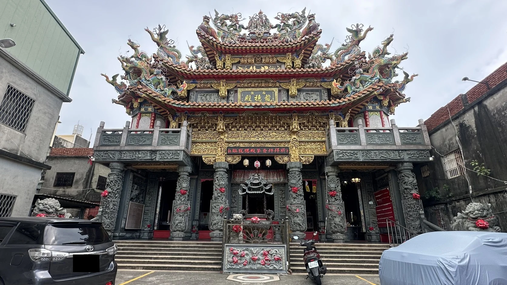龍穗殿的匾額與屋脊剪黏，廟前是階梯與停車空間