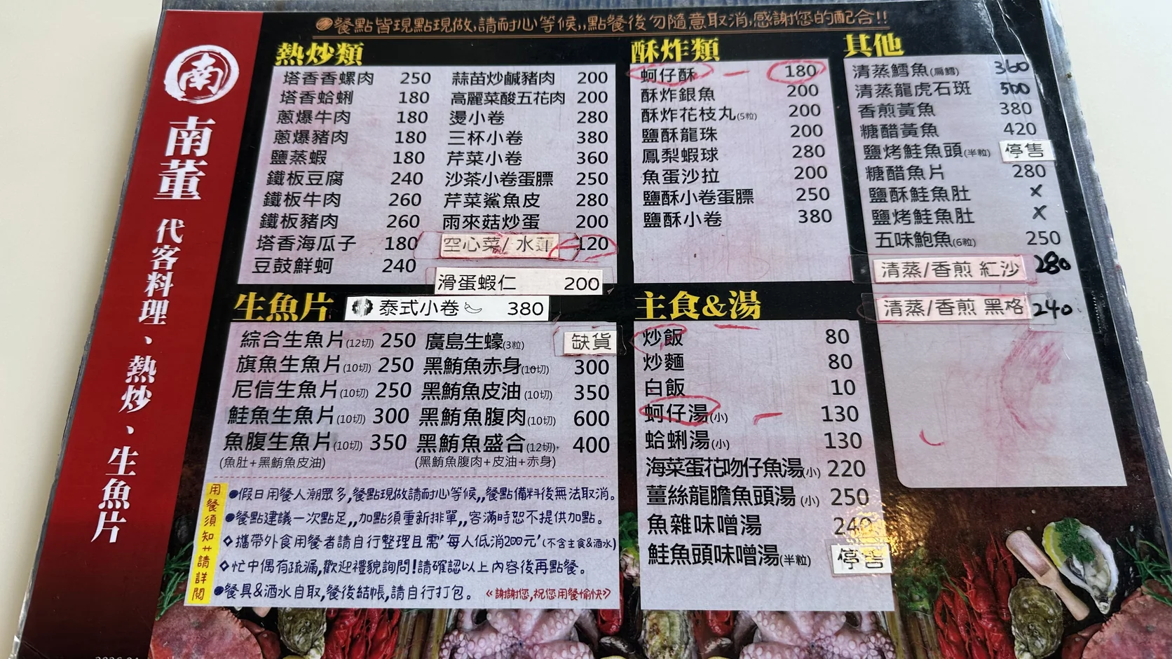 南董店內菜單：分成熱炒、酥炸、生魚片、主食與湯等區塊，並寫有現點現做、外食低消與餐具酒水自取的用餐須知