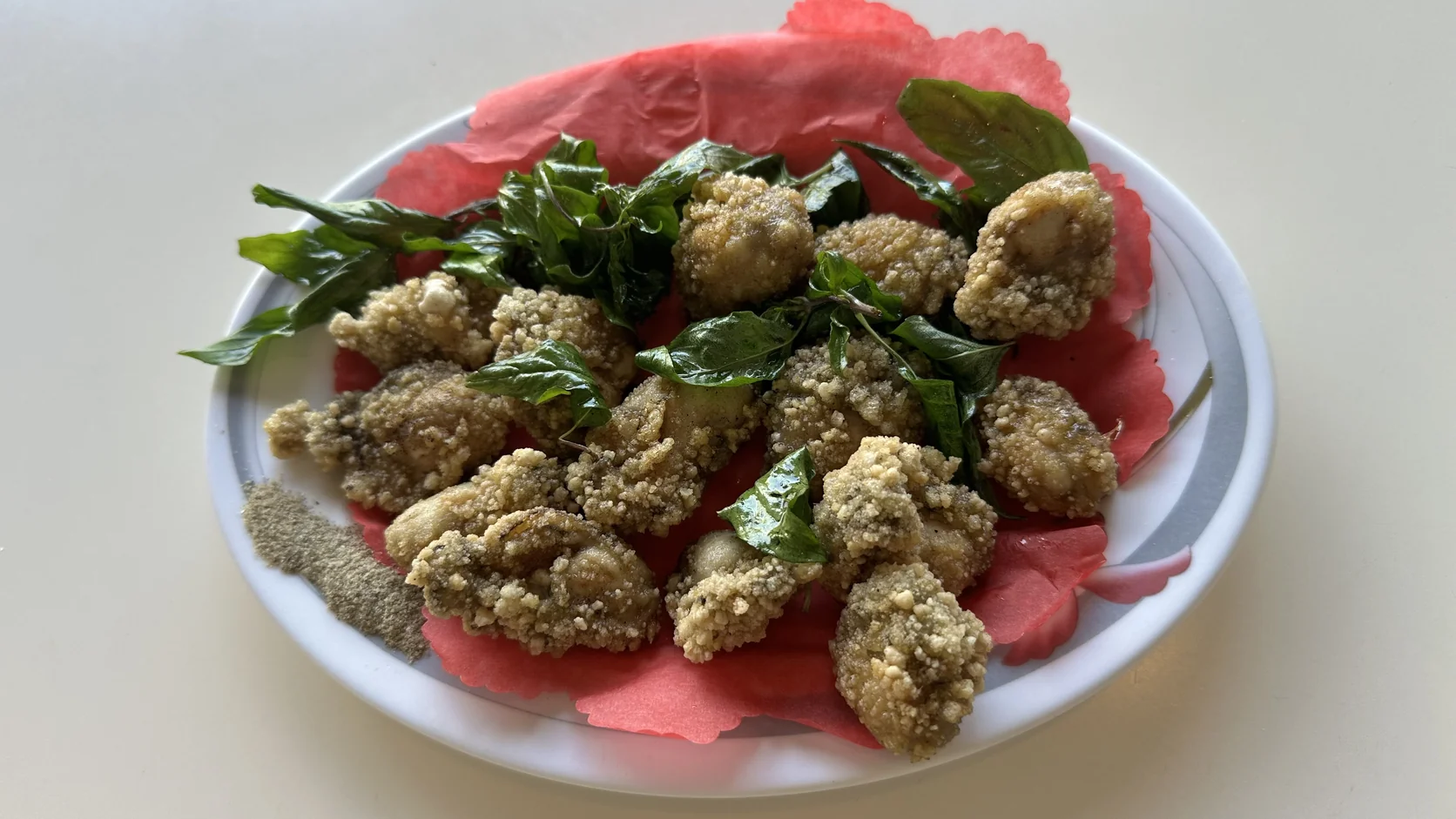 蚵仔酥：鴿子蛋大小的酥炸蚵仔，搭配炸九層塔，墊在紅色吸油紙上，盤邊附胡椒粉