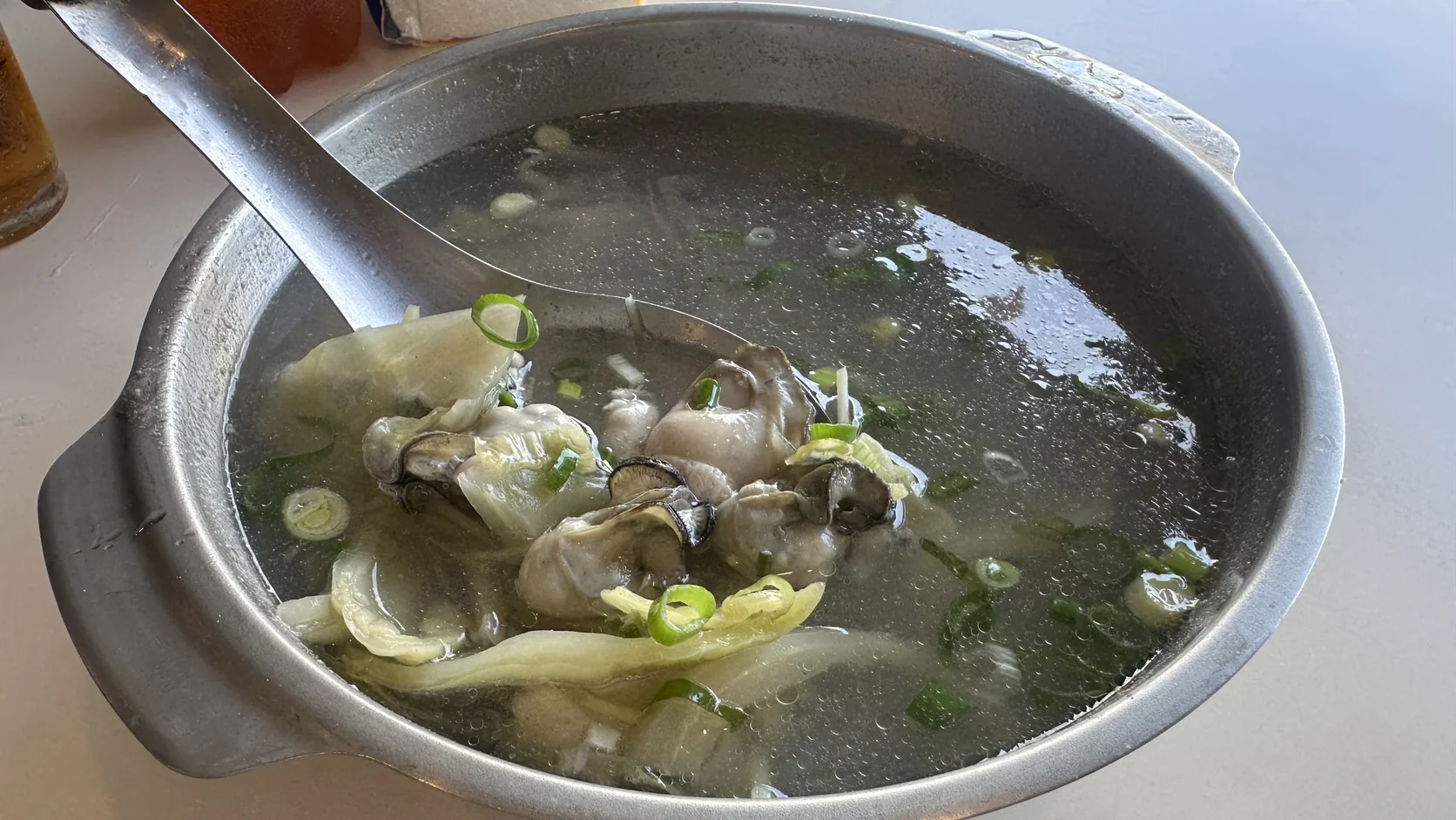 蚵仔湯：金屬湯鍋裡盛著蚵仔、葉菜與蔥花