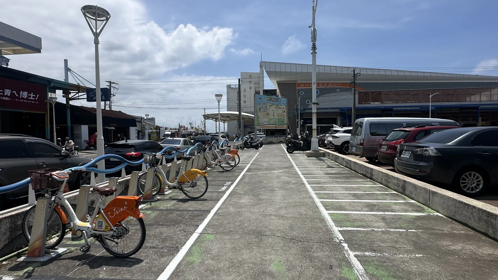 停車場內的停車格與 YouBike 站點，遠處是魚貨直銷中心