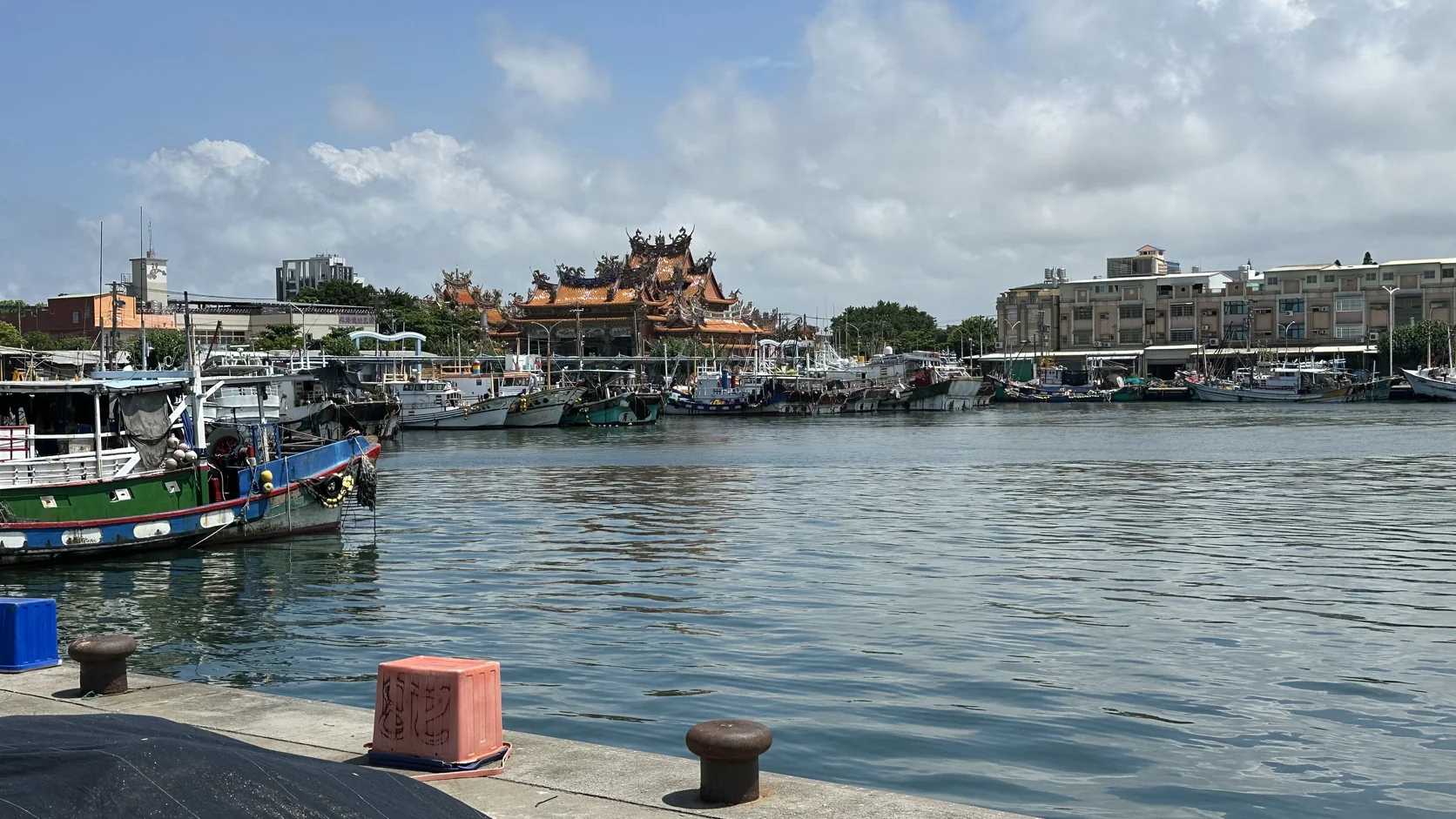港池全景：漁船與碼頭繫船柱在前，遠處漁船與房舍之間露出宮廟屋頂