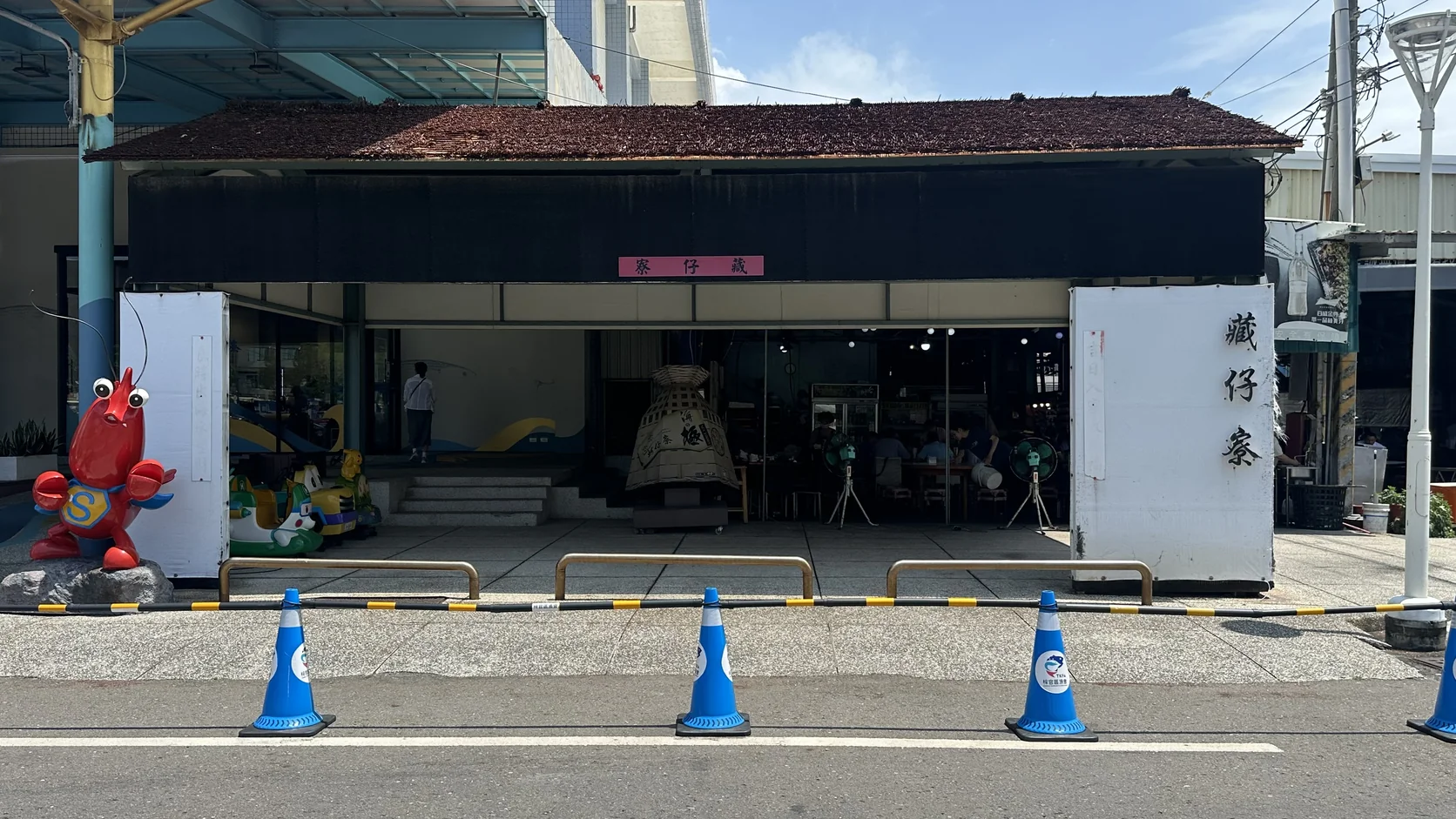 停車場旁的戀戀蚵仔寮外觀，門口有造型龍蝦吉祥物