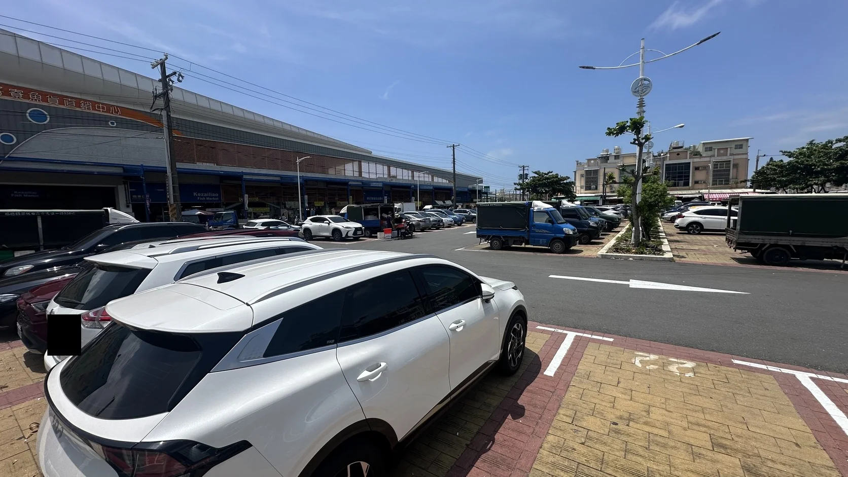 魚市場旁的停車場全景與整排停放的車輛，車牌已遮蔽