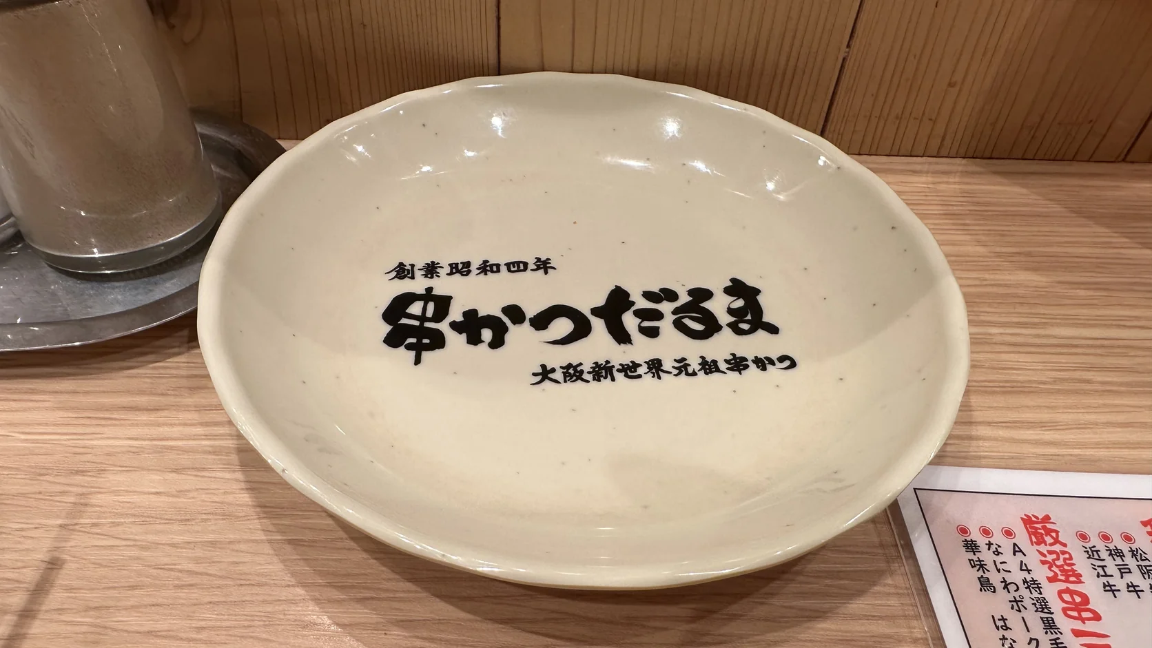 串かつだるま的個人小盤特寫，盤面印有「創業昭和四年」「串かつだるま」「大阪新世界元祖串かつ」