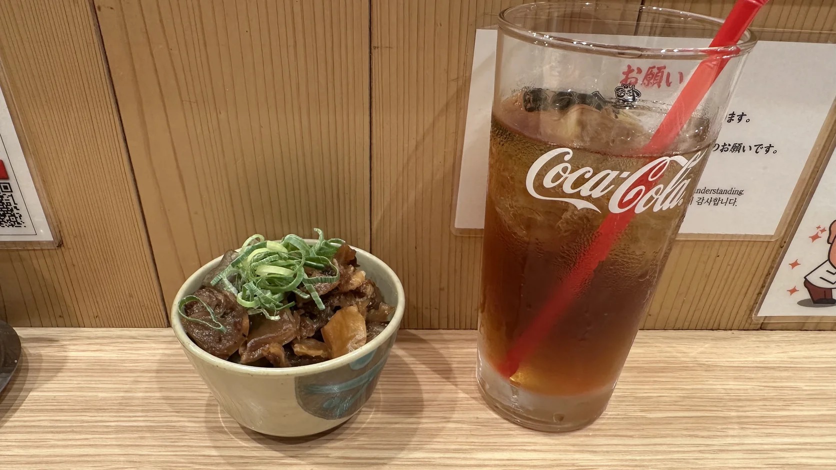 串かつだるま的桌面，有木製圓筒、黑色串炸醬擠壓瓶與三罐粉狀調味料，後方貼有官方App的QR Code
