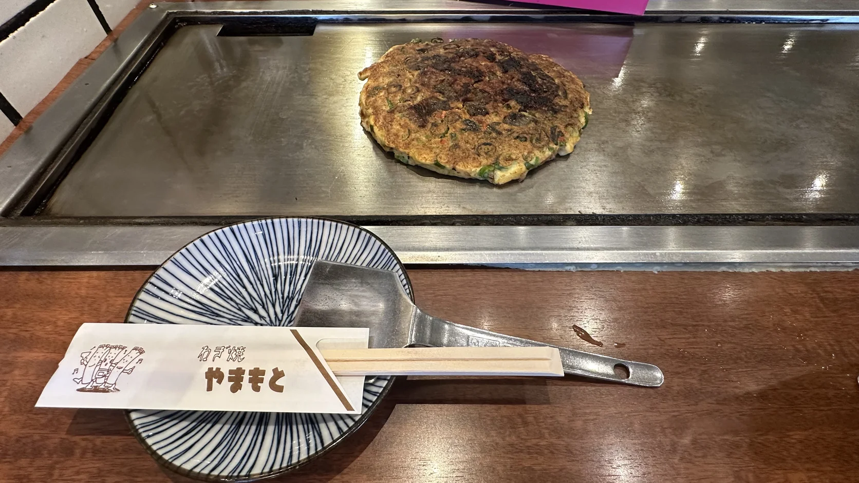 牛筋蔥燒完成後直接放在客人面前的鐵板上，旁邊是小盤、小鏟子與竹筷