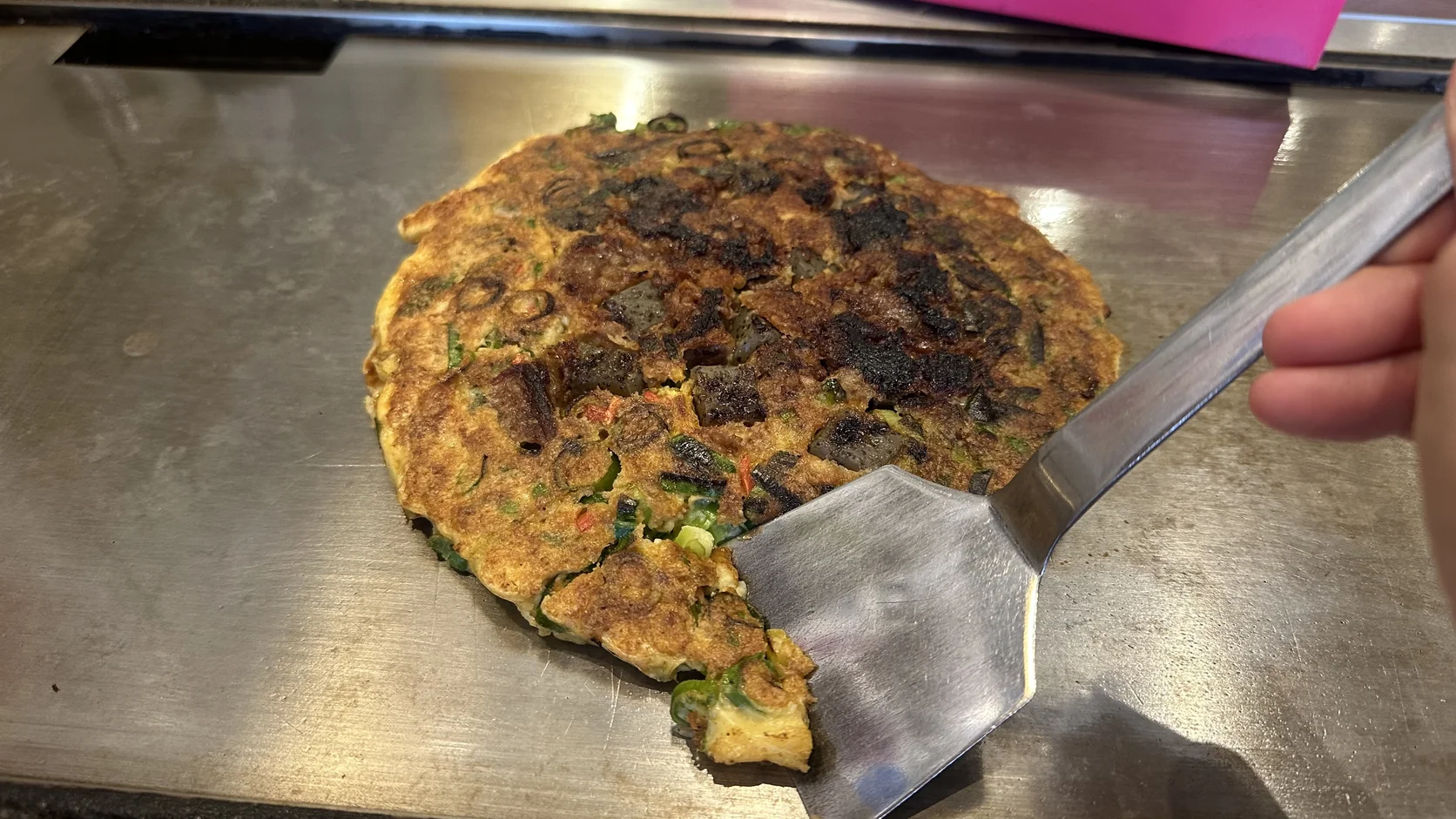 小鏟子切開一角的牛筋蔥燒，剖面可以看到青蔥與柔軟的餅體
