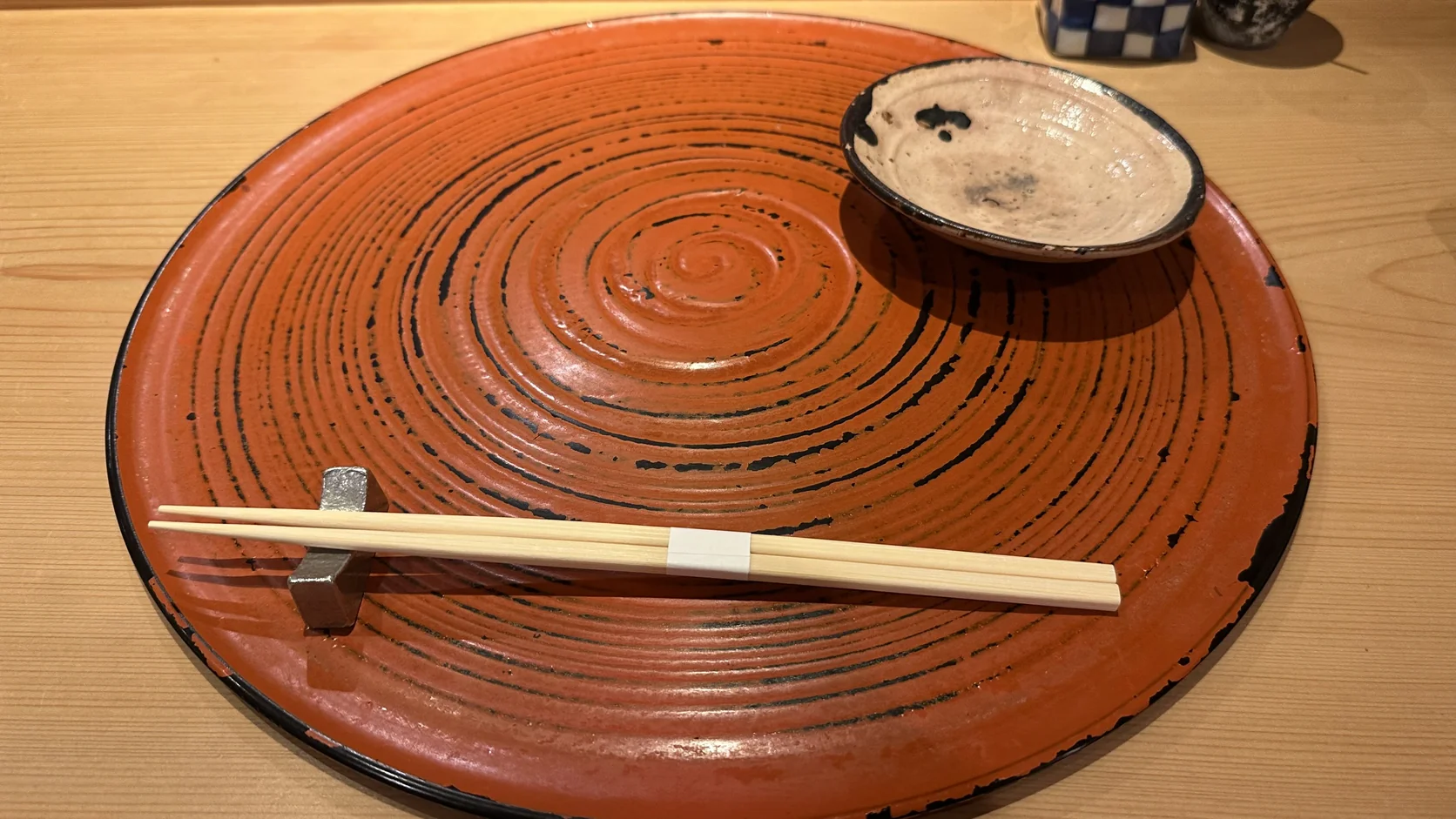 朱紅色圓形大餐盤、筷架與小碟子，擺在天星的吧檯座位前