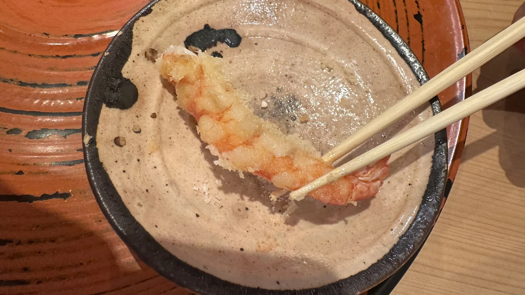 陶盤上的蝦身天婦羅，以筷子夾起