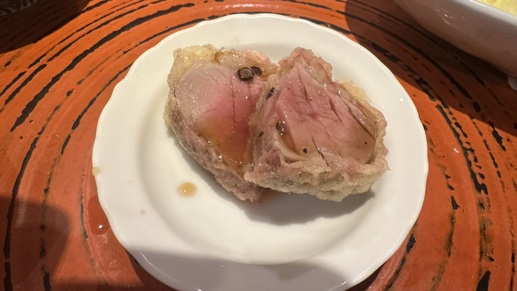 切開後肉心粉嫩的鴨肉天婦羅，淋著少量醬汁