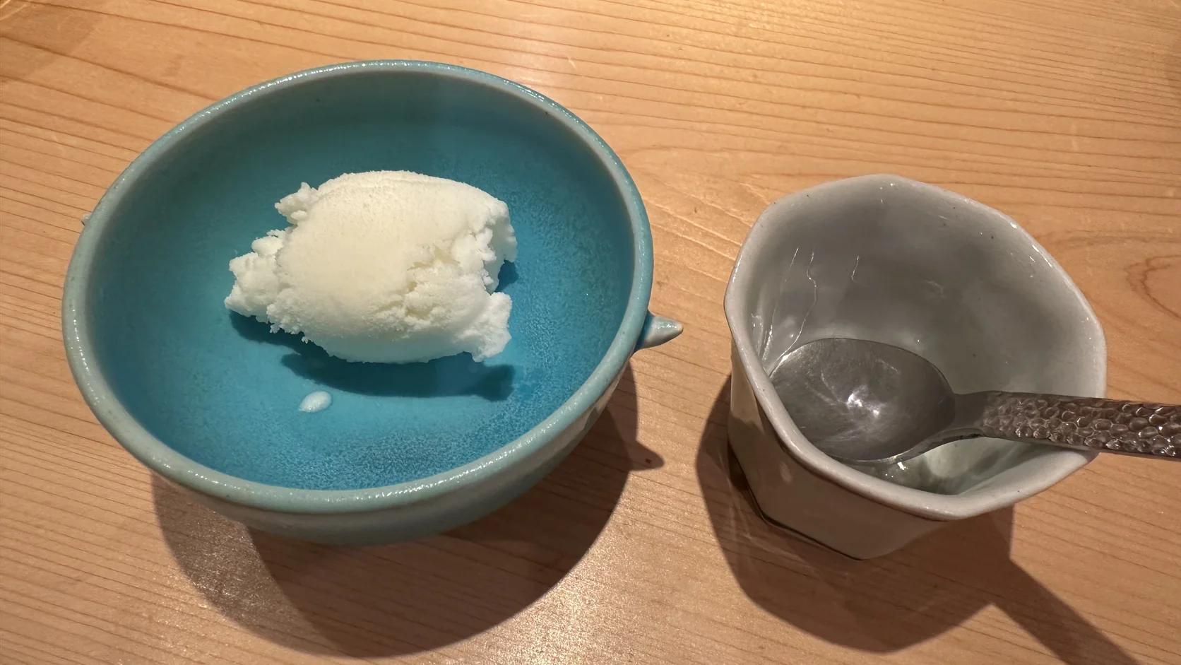 湖水綠色小碗中的一球白色冰品，帶有微酸味